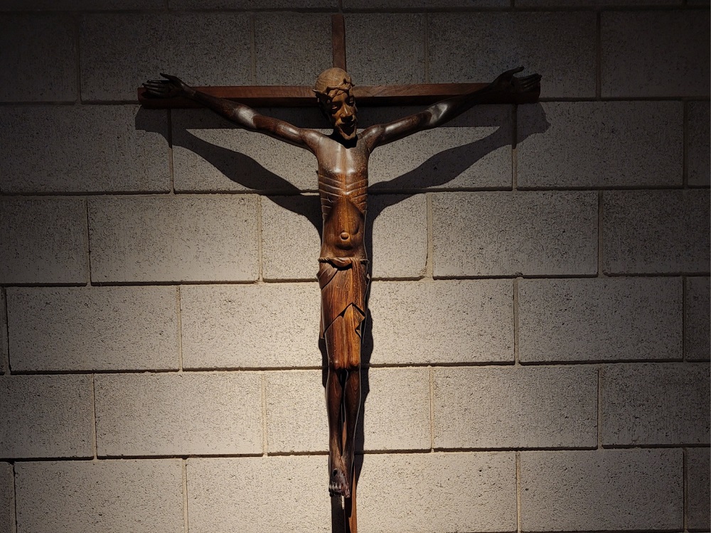 Wooden African style crucifix hanging on cement block wall