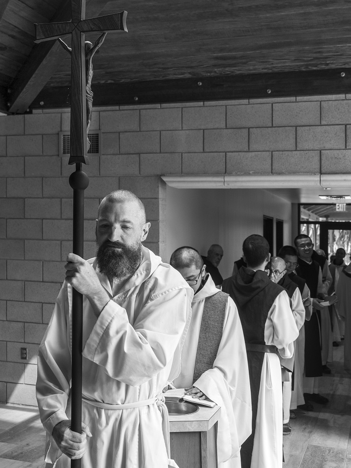 black and white photo of monks in procession lead by a monk holding the crucifix