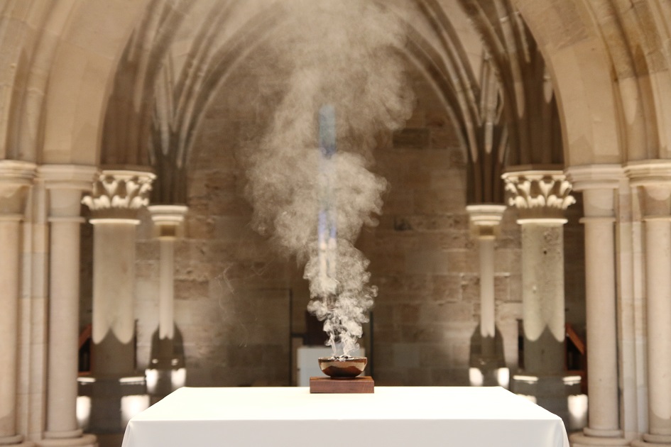 Incense rising from a bowl set on altar in gothic stone church