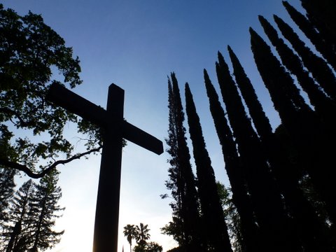 Large Cross at sunrise surrounded by trees
