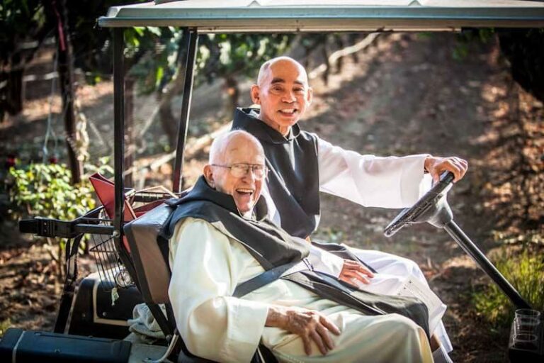 Br. William and Fr. Bernard in a golf cart in front of the vineyard